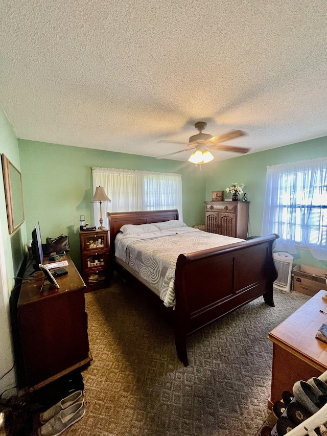 bedroom featuring a textured ceiling, ceiling fan, and dark carpet