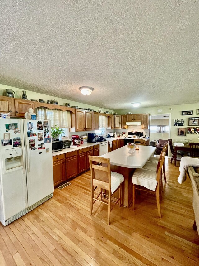 kitchen featuring light hardwood / wood-style floors, a textured ceiling, and white appliances