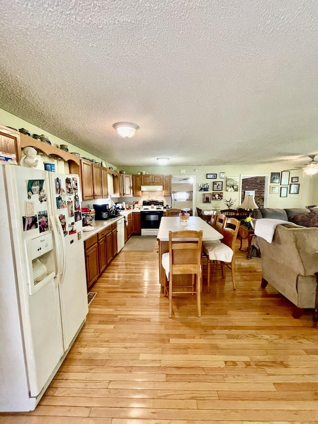 kitchen with white appliances, ceiling fan, a textured ceiling, and light wood-type flooring