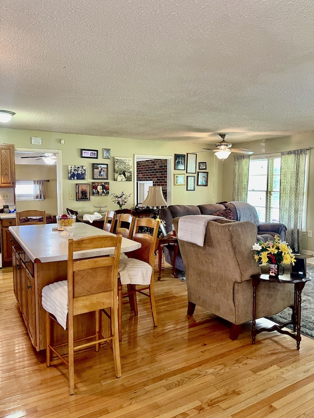 dining area with light wood-type flooring, a textured ceiling, and ceiling fan