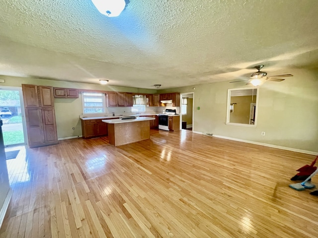 kitchen featuring a healthy amount of sunlight, light hardwood / wood-style flooring, a kitchen island, and electric range