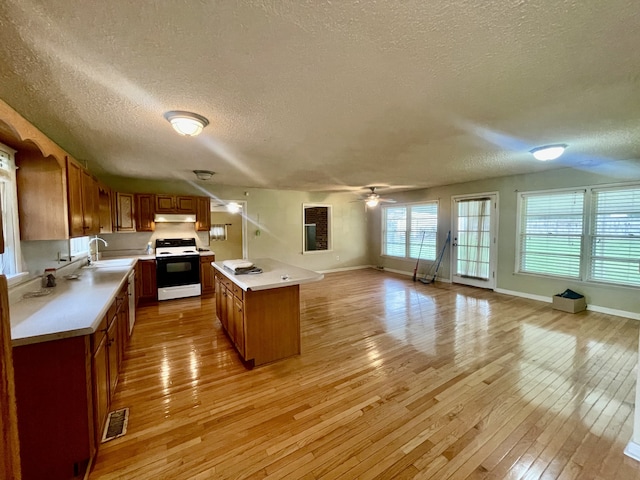 kitchen featuring a textured ceiling, light wood-type flooring, white range oven, and ceiling fan