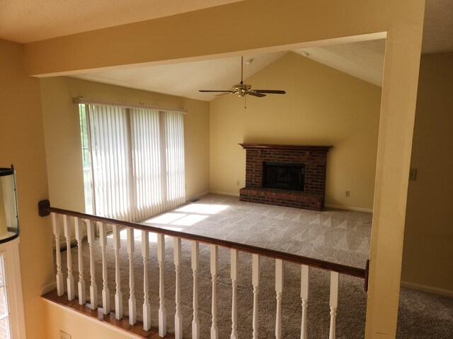 unfurnished living room featuring vaulted ceiling, a brick fireplace, carpet flooring, and ceiling fan