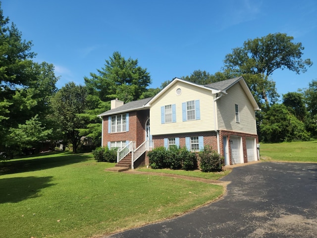 split foyer home with a garage, a front yard, aphalt driveway, and brick siding