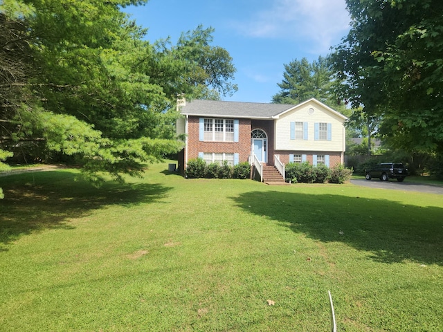 raised ranch with brick siding, a front lawn, and a chimney