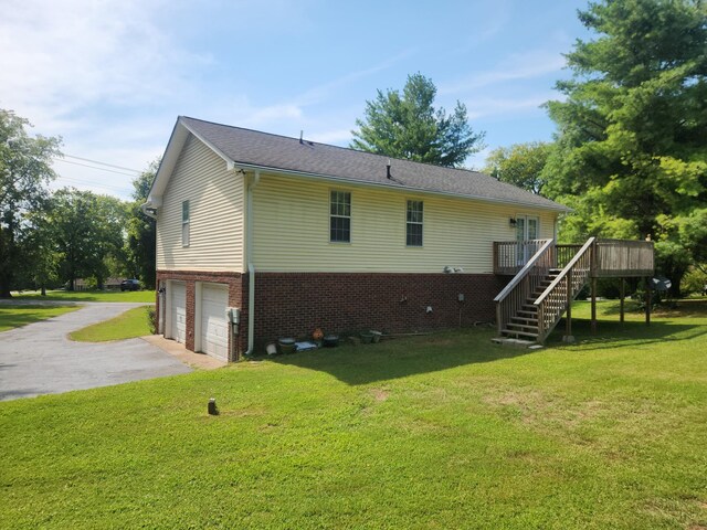 back of house featuring a garage, a yard, and a deck