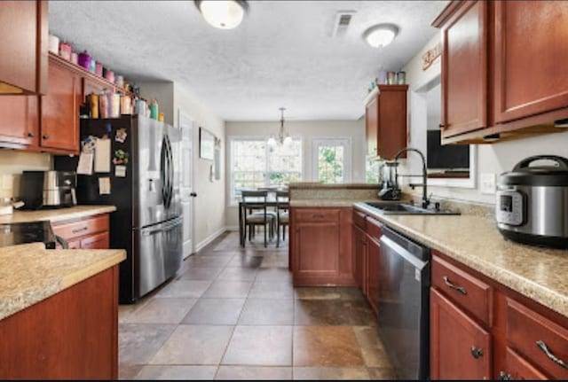 kitchen with sink, light tile patterned floors, appliances with stainless steel finishes, a textured ceiling, and decorative light fixtures