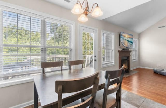 dining area featuring lofted ceiling, hardwood / wood-style floors, and a chandelier