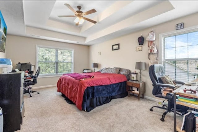 bedroom with a tray ceiling and light carpet