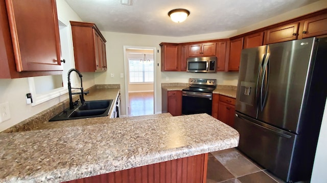 kitchen with appliances with stainless steel finishes, sink, and kitchen peninsula