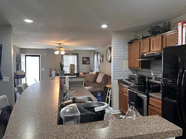 kitchen featuring tasteful backsplash, black fridge with ice dispenser, brown cabinetry, stainless steel range with electric cooktop, and under cabinet range hood