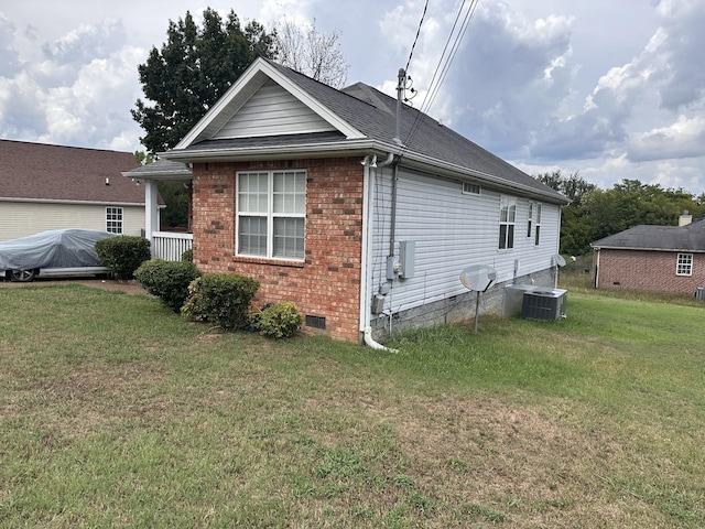 view of side of property featuring a shingled roof, central AC unit, a lawn, crawl space, and brick siding