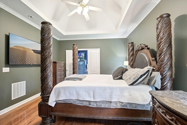 bedroom with hardwood / wood-style flooring, ceiling fan, ornamental molding, and a raised ceiling