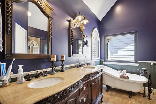 bathroom featuring vanity, a wealth of natural light, vaulted ceiling, and a tub