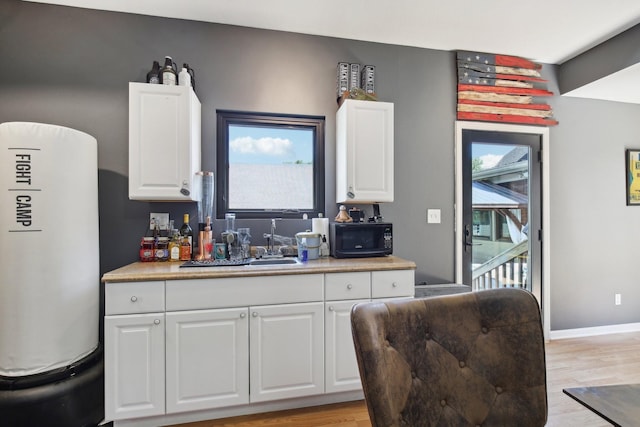 kitchen featuring white cabinetry, sink, and light hardwood / wood-style flooring