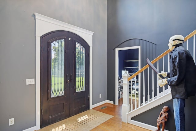 entrance foyer featuring hardwood / wood-style flooring, french doors, and a towering ceiling