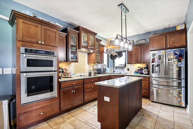 kitchen with a kitchen island, tasteful backsplash, appliances with stainless steel finishes, and hanging light fixtures