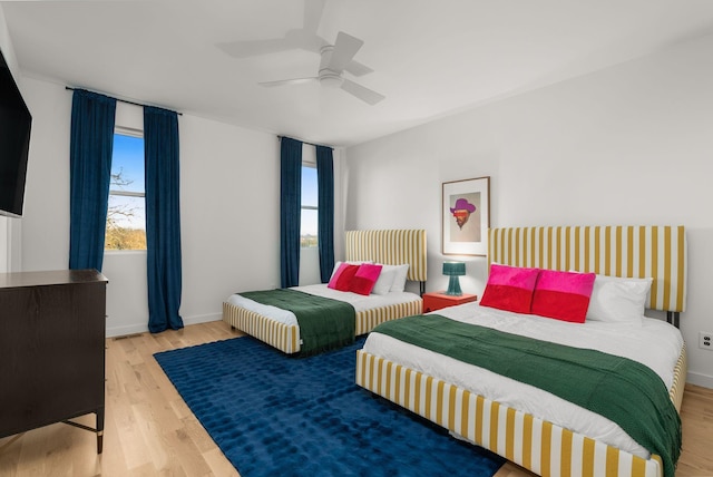 bedroom featuring ceiling fan, multiple windows, and light hardwood / wood-style flooring