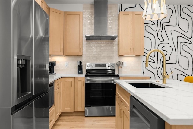 kitchen featuring appliances with stainless steel finishes, light brown cabinetry, and wall chimney range hood