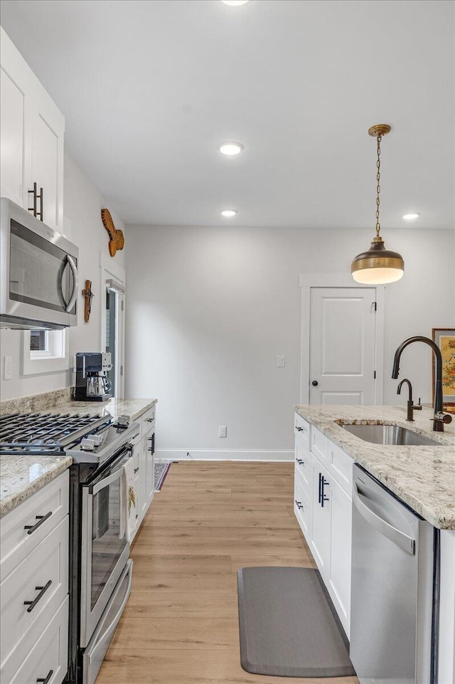 kitchen with white cabinetry, sink, pendant lighting, and stainless steel appliances