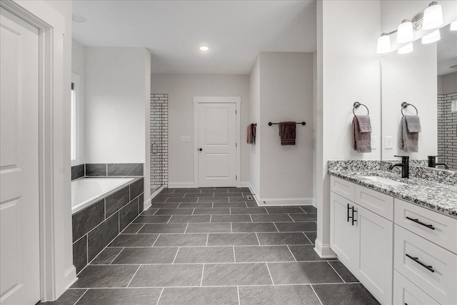 bathroom featuring tiled tub and vanity