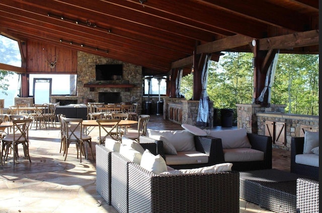 view of patio with outdoor dining area, an outdoor living space with a fireplace, and a bar