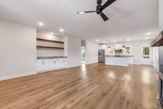 unfurnished living room featuring ceiling fan, a healthy amount of sunlight, and light wood-type flooring