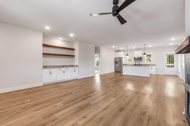 unfurnished living room with light wood finished floors, recessed lighting, ceiling fan, and baseboards
