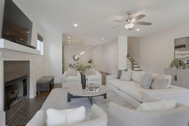 living room with dark wood-type flooring, ceiling fan, and a fireplace