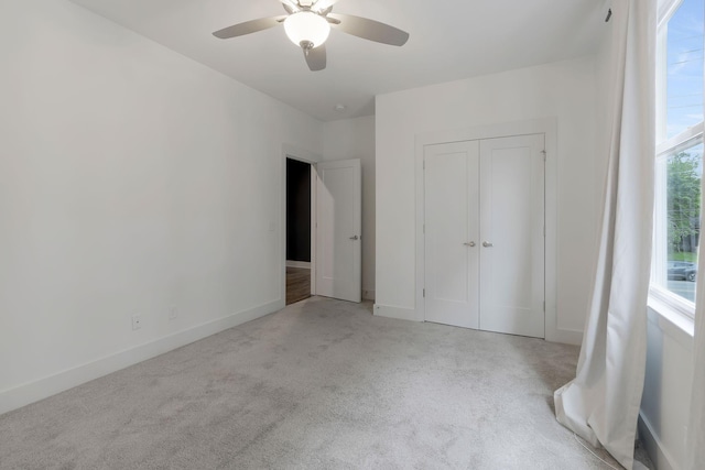 unfurnished bedroom featuring ceiling fan, a closet, and light carpet