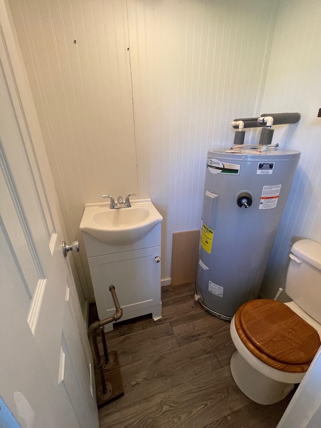 bathroom featuring hardwood / wood-style flooring, vanity, toilet, and electric water heater