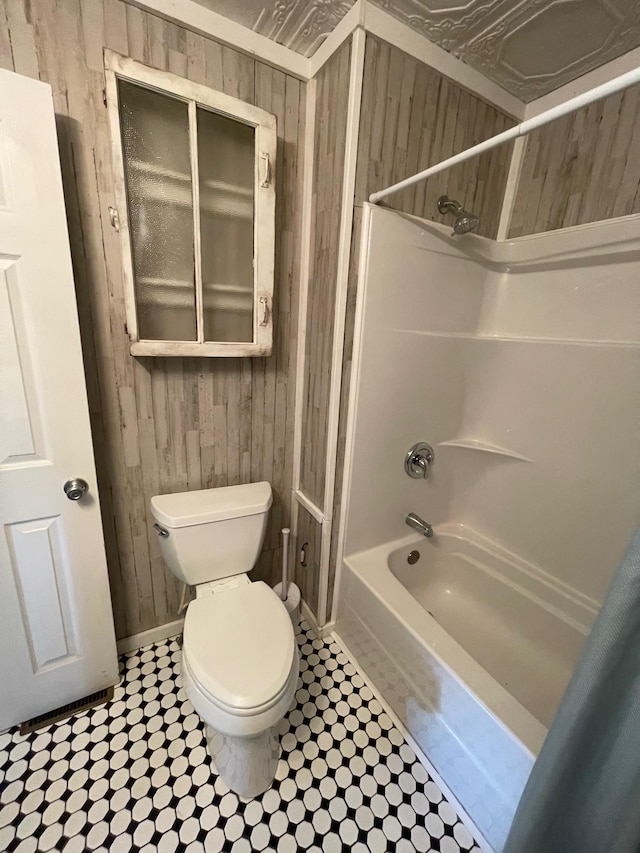 bathroom with  shower combination, toilet, and wood walls