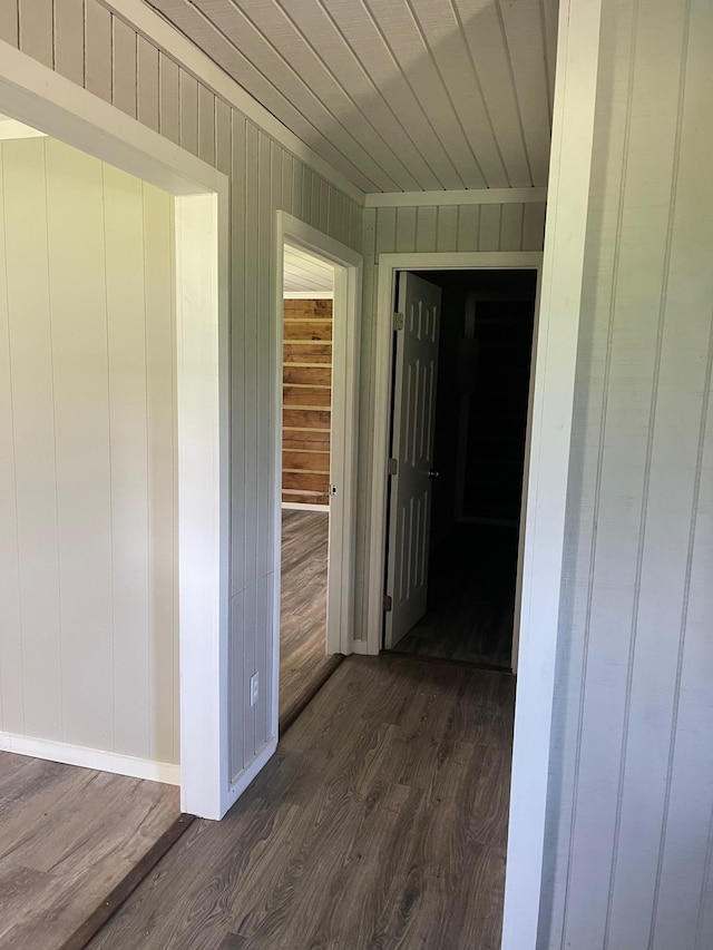 hallway featuring dark wood-type flooring, wooden walls, and wooden ceiling