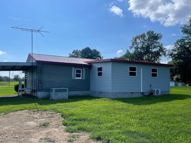 back of property with central AC, a lawn, and ac unit