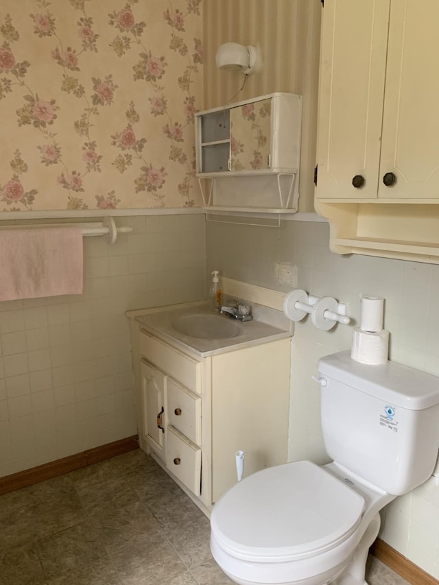 bathroom featuring vanity, tile walls, and toilet