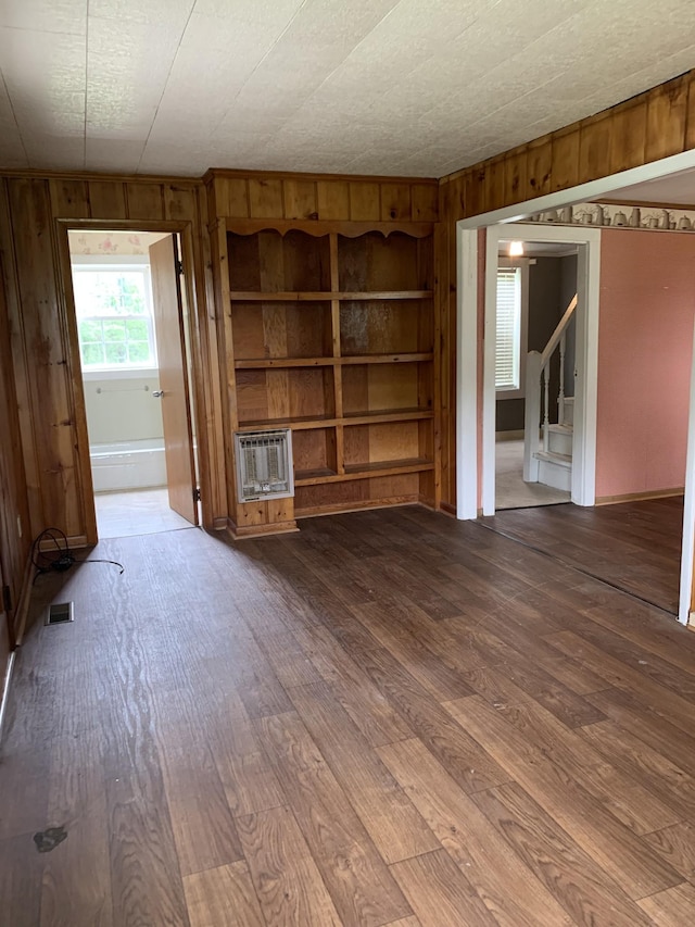 unfurnished living room featuring hardwood / wood-style flooring and wooden walls