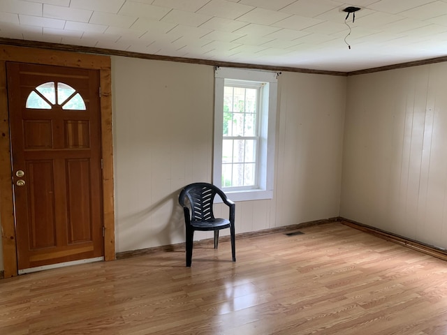 entryway with ornamental molding and light wood-type flooring