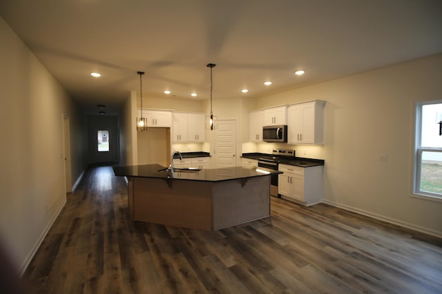 kitchen featuring stainless steel appliances, white cabinetry, dark hardwood / wood-style floors, and a center island with sink