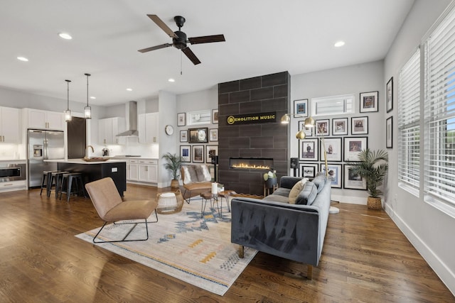 living room with ceiling fan, dark hardwood / wood-style floors, sink, and a fireplace