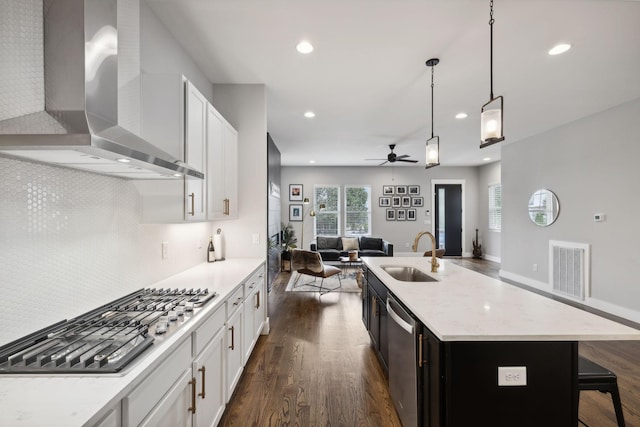 kitchen featuring white cabinetry, sink, wall chimney range hood, and a kitchen island with sink