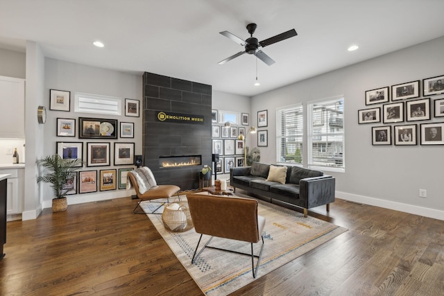 living room with dark wood-type flooring, ceiling fan, and a fireplace