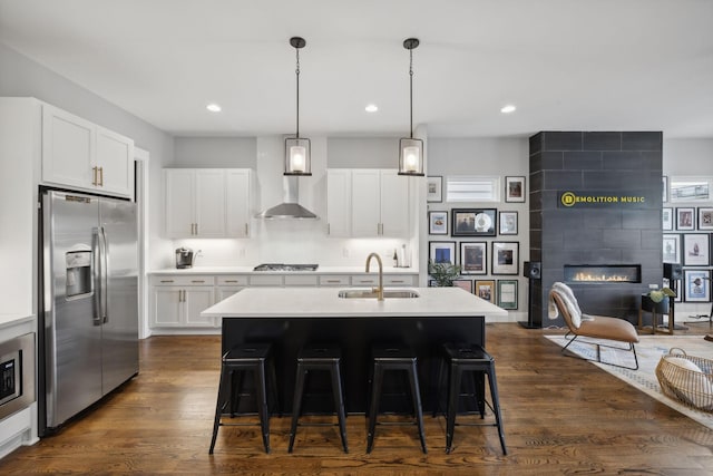 kitchen featuring sink, white cabinetry, decorative light fixtures, appliances with stainless steel finishes, and a kitchen island with sink