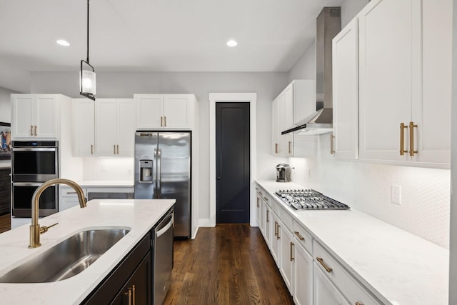 kitchen featuring white cabinetry, wall chimney range hood, stainless steel appliances, and sink