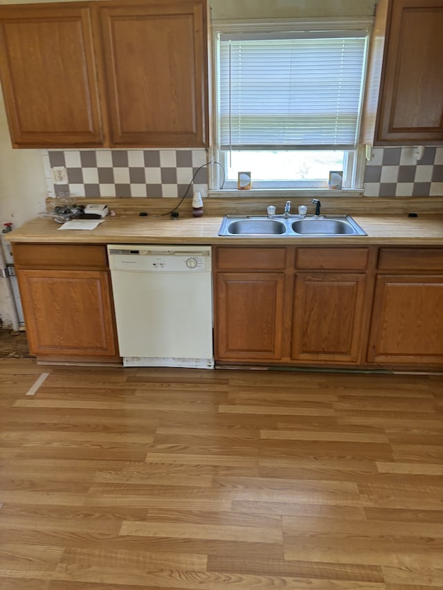 kitchen with light wood-type flooring, backsplash, sink, and white dishwasher