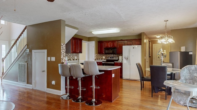 kitchen with tasteful backsplash, an inviting chandelier, light hardwood / wood-style flooring, stainless steel electric stove, and white refrigerator with ice dispenser