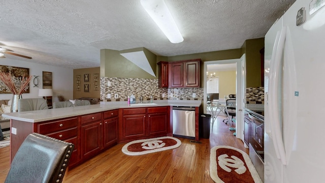 kitchen with sink, light hardwood / wood-style flooring, stainless steel dishwasher, kitchen peninsula, and white fridge