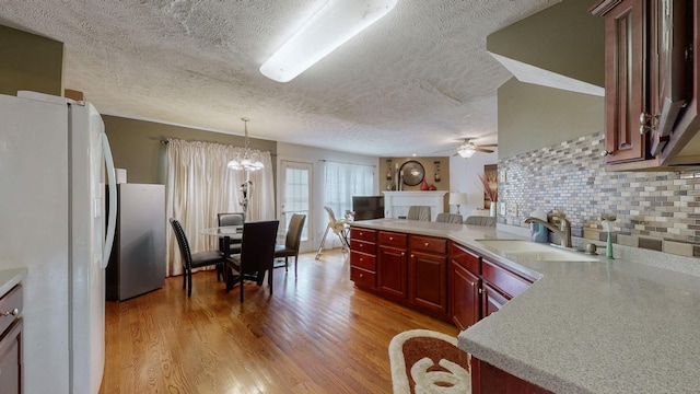 kitchen with pendant lighting, sink, decorative backsplash, white fridge, and light wood-type flooring