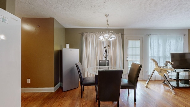 dining area with hardwood / wood-style floors, a notable chandelier, and a textured ceiling