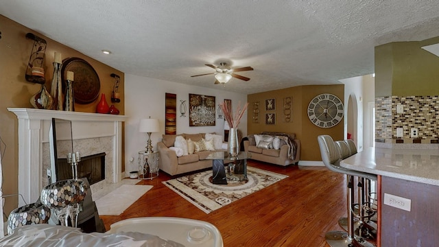 living room featuring dark hardwood / wood-style flooring, ceiling fan, a textured ceiling, and a fireplace