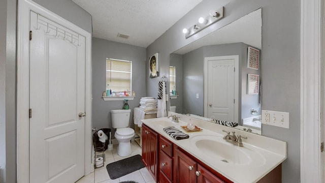 bathroom with tile patterned flooring, vanity, a textured ceiling, a tub to relax in, and toilet